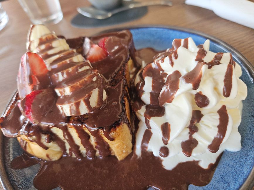 Brioche with banana, strawberries, chocolate sauce, and whipped cream