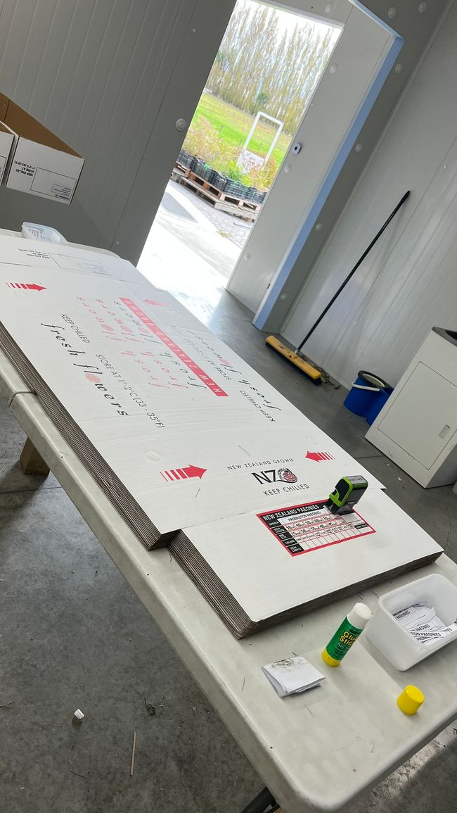 Die Boxendeckel werden gestempelt und beklebt, bevor sie zusammengetackert werden.