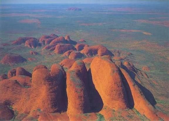 Kata Tjuta bedeutet auf Deutsch "Viele Köpfe" oder "Viele Köpfe" (wörtlich), ein Name der Aborigines für die riesige Gruppe von 36 Felskuppeln (auch als die Olgas bekannt) nahe dem Uluru in Australien, die eine heilige Stätte der Anangu sind und sich durch ihre sich ändernden Farben und Schluchten auszeichnen.