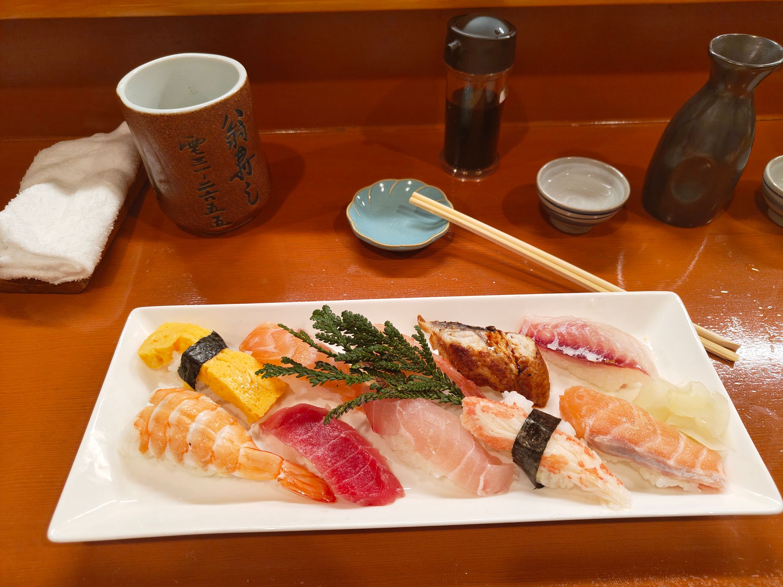 Nigiri avec différents types de poisson, accompagné de thé vert et un peu de saké