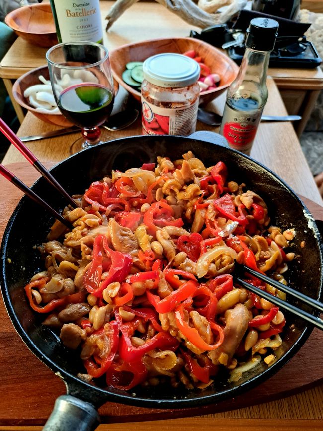 Spicy aus der Gusseisenpfanne: köstlich pikantes Kung pao chicken á la maison mit sieben roten höllisch-scharfen Chillis an einem Quartett von frischer roter Paprika, knackigen Zwiebeln aus der Crau, aromatischem Ingwer und gesalzenen Erdnüssen, gekrönt von einer farbenfrohen Garnitur von Frühlingszwiebelgrün