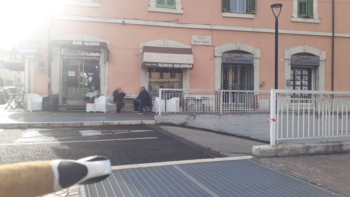 Two gentlemen in front of the bar in Terni. They are not bothered by the traffic noise.