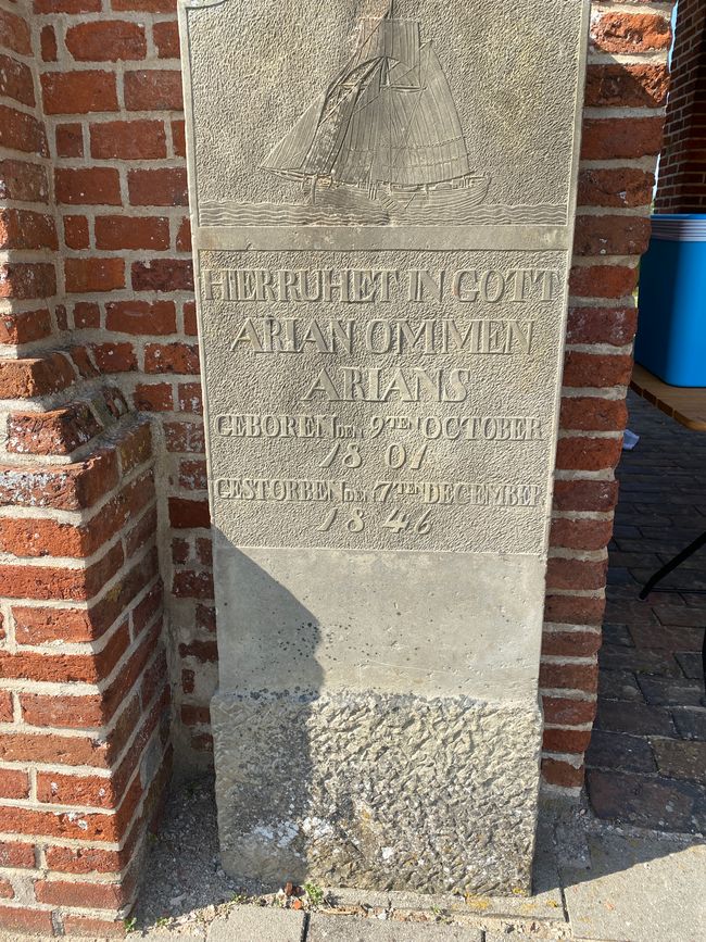 Am Glockenturm steht ein alter Grabstein