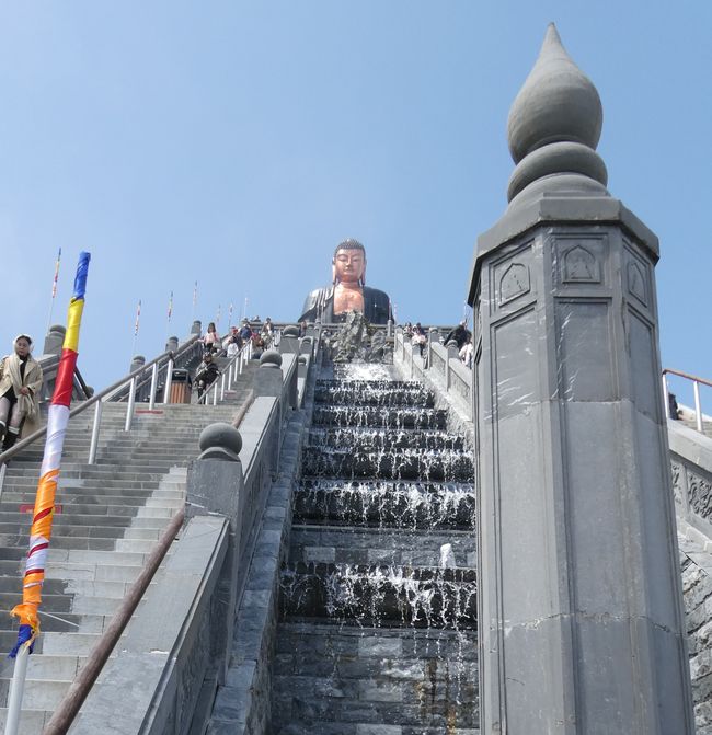 El Fansipan es la montaña más alta de Indochina. Indochina, un nombre que los europeos han dado a este subcontinente. La tierra entre India y China. Así de poco imaginativos son los colonialistas. De todos modos, pensamos que sería una buena idea reservar el viaje en góndola hasta el Fansipan. No lo haríamos de nuevo. Puro turismo masivo, pero gestionado de manera profesional. Un teleférico construido por un ingeniero austriaco supera una diferencia de altura de casi 1700 metros en 15 minutos. Se dice que a pie, para una persona joven y en forma, tomaría seis horas. No somos ni jóvenes ni estamos en forma... Arriba se puede admirar lo que sobre todo la comunidad budista de Vietnam ha logrado. También esto es adecuado para muchas personas. Después, hacemos otra parada para almorzar y luego tenemos que soportar el largo viaje de regreso a Hanoi. Esperando para la góndola Esperando para la góndola Gran instalación para muchos turistas Gran instalación para muchos turistas El Buda de bronce más grande de Vietnam El Buda de bronce más grande de Vietnam Los cuatro reyes celestiales vigilan al Buda Los cuatro reyes celestiales vigilan al Buda Estábamos arriba y no solos Estábamos arriba y no solos   Guanyin, Bodhisattva de la Compasión Guanyin, Bodhisattva de la Compasión Primer selfie con trípode Primer selfie con trípode Fuente