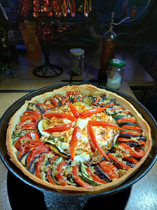 Tarte provençal - harmonisch gelegtes Dreierlei von feinst geschnittener marktfrischer Tomate, Zucchini und Aubergine auf einem Herz von gebackenem Knoblauch-Feta in einem Nest aus hauchdünnen Porreeringen mit Oignon rosé de Roscoff, sanft gegart einem Sud aus elf, im Mörser mit Kräutern der Provence und bestem Olivenöl gestoßenen frischen Knoblauchzehen 