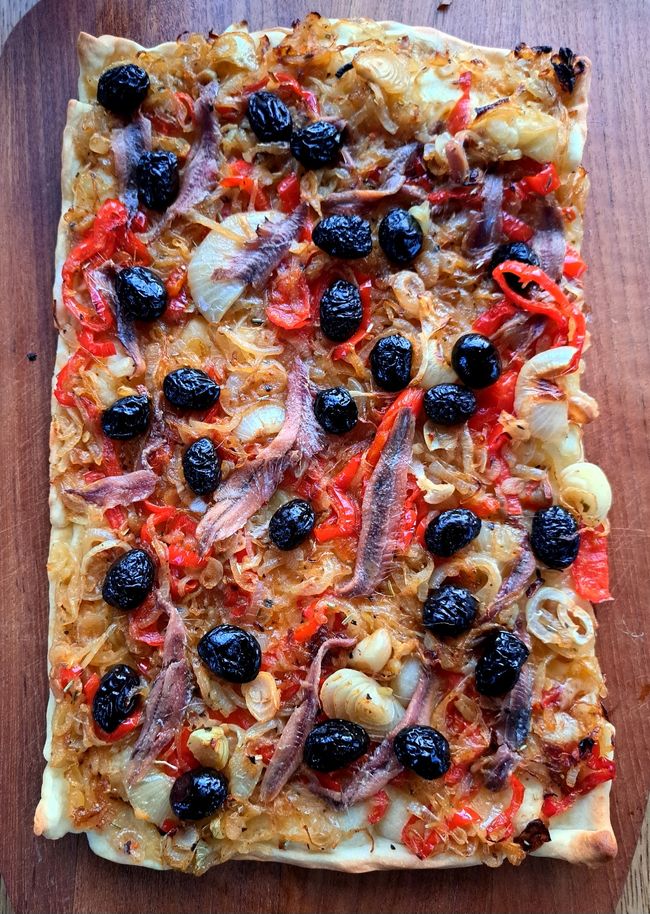 Dann mit Oliven und Anchovis auf den Teig, die Paprika sind auch nicht original, mit Pfeffer abschmecken.