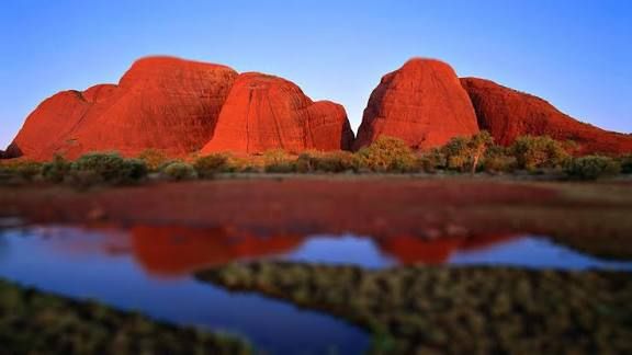 Kata Tjuta bedeutet auf Deutsch "Viele Köpfe" oder "Viele Köpfe" (wörtlich), ein Name der Aborigines für die riesige Gruppe von 36 Felskuppeln (auch als die Olgas bekannt) nahe dem Uluru in Australien, die eine heilige Stätte der Anangu sind und sich durch ihre sich ändernden Farben und Schluchten auszeichnen.