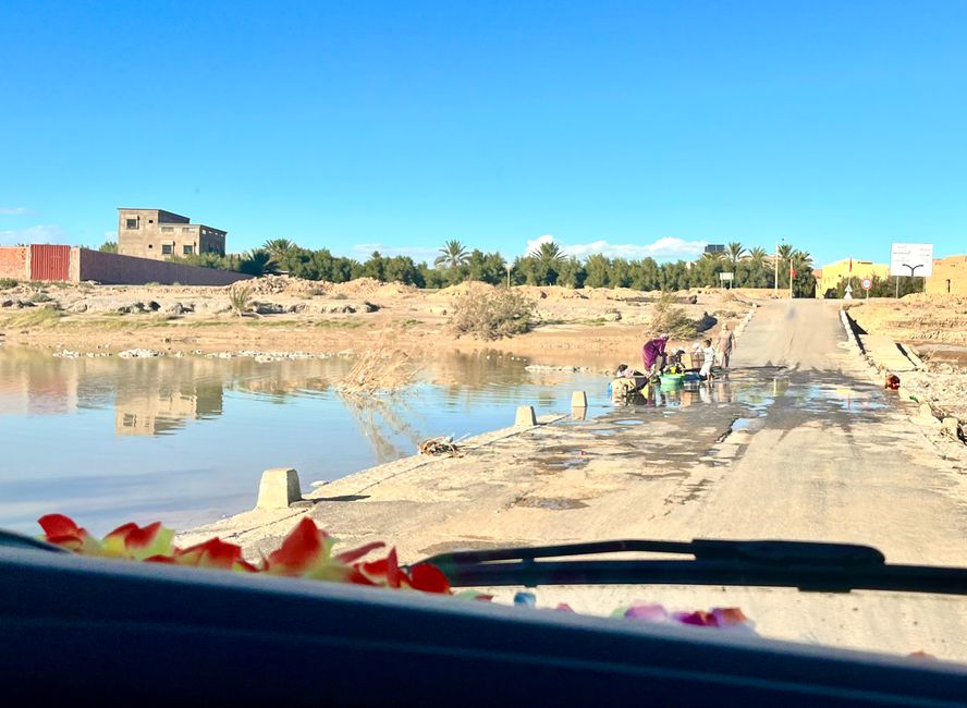 Washing clothes and carpets at a river with typical Moroccan crossing of the wadi