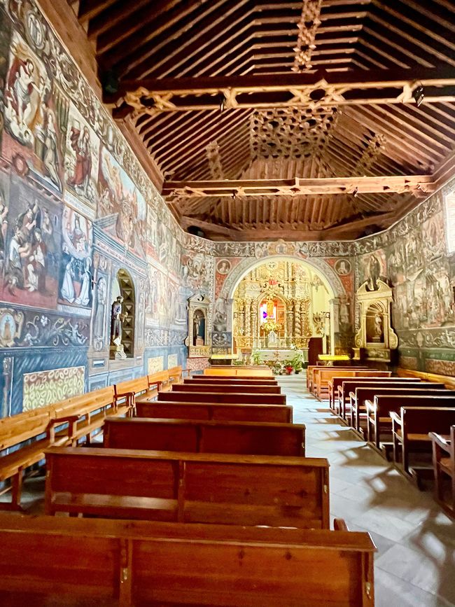 The church has a wooden ceiling and the walls are painted with pictures throughout.