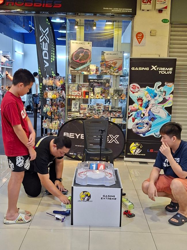 Guys playing the game "fighting tops" at Prangin Mall