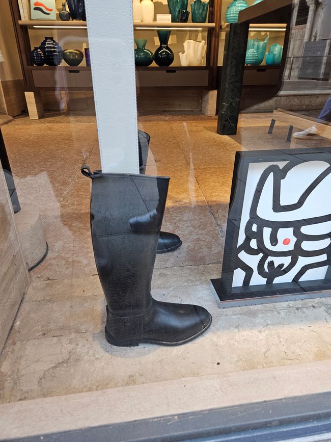 Tisch im Schaufenster nahe des Markusplatzes mit Gummistiefeln 